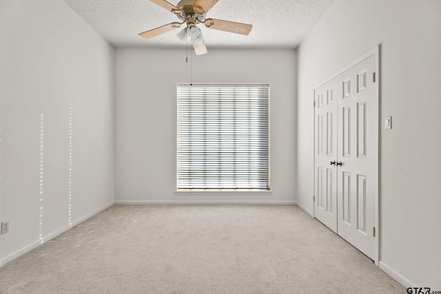 carpeted spare room featuring ceiling fan, a textured ceiling, and a wealth of natural light