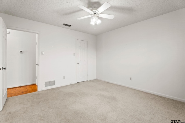 unfurnished bedroom featuring light colored carpet, a textured ceiling, and ceiling fan