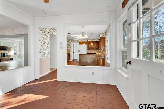 interior space with tile patterned floors, sink, an inviting chandelier, white fridge with ice dispenser, and pendant lighting