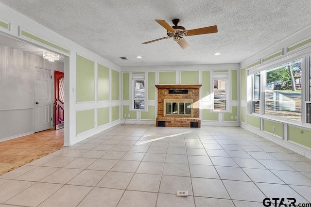 unfurnished living room featuring light tile patterned flooring, a brick fireplace, a textured ceiling, and ceiling fan