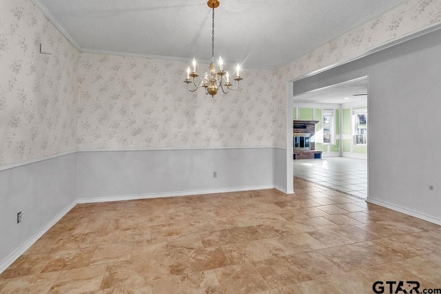 unfurnished room with ornamental molding, a notable chandelier, and a fireplace