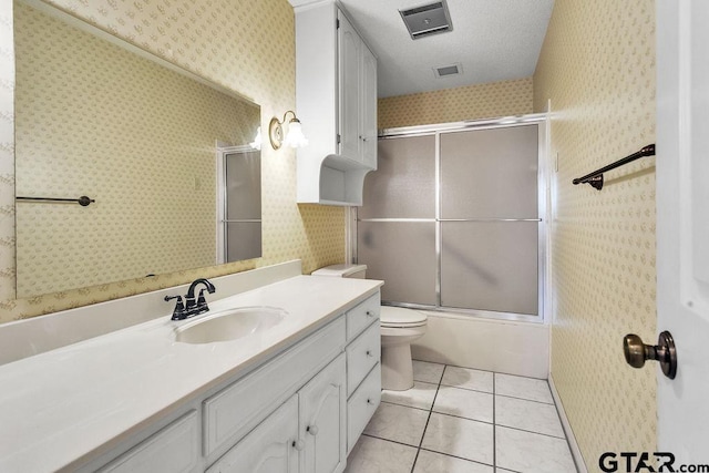 full bathroom featuring shower / bath combination with glass door, tile patterned flooring, vanity, a textured ceiling, and toilet