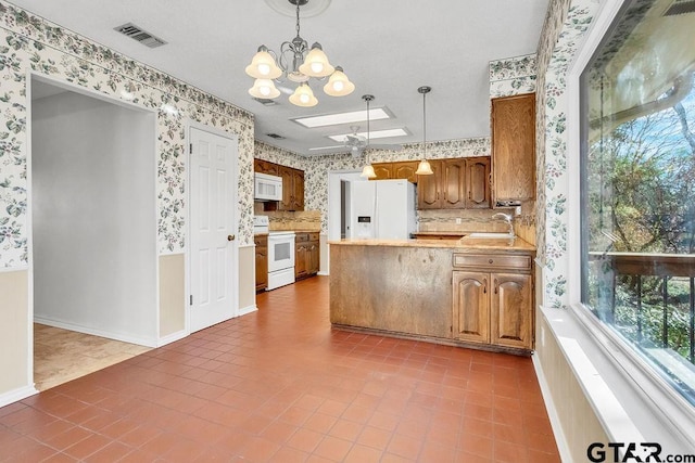 kitchen with tile patterned floors, sink, a skylight, hanging light fixtures, and white appliances