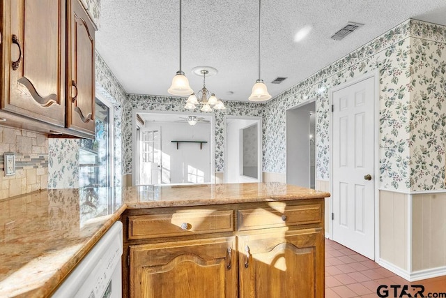 kitchen featuring dishwasher, dark tile patterned floors, light stone countertops, a textured ceiling, and decorative light fixtures