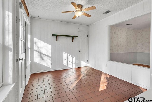 spare room with tile patterned flooring, a textured ceiling, a wealth of natural light, and ceiling fan