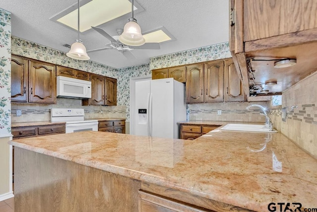 kitchen featuring pendant lighting, sink, ceiling fan, kitchen peninsula, and white appliances