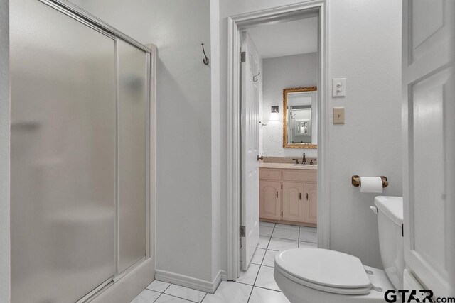 bathroom featuring tile patterned flooring, vanity, a shower with door, and toilet