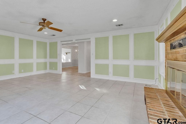 spare room with light tile patterned floors, a fireplace, and ceiling fan