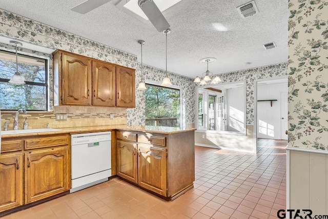 kitchen with hanging light fixtures, dishwasher, sink, and light tile patterned floors