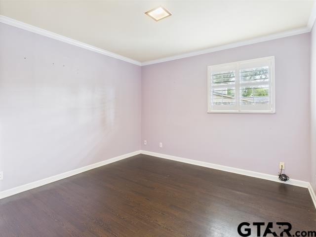 3323 S Keaton Ave, Tyler, TX 75701 - empty room featuring baseboards, ornamental molding, and dark wood-style floors