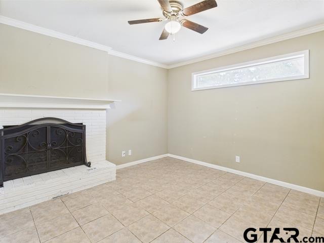 3323 S Keaton Ave, Tyler, TX 75701 - unfurnished living room with ceiling fan, a brick fireplace, tile patterned floors, baseboards, and ornamental molding