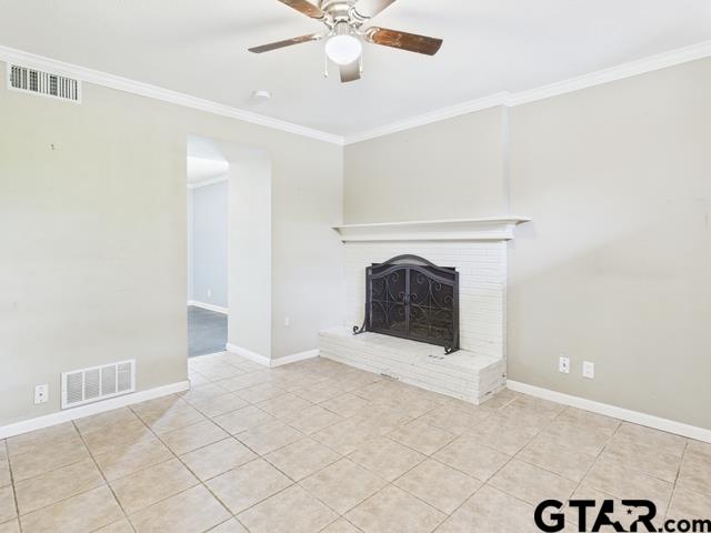 3323 S Keaton Ave, Tyler, TX 75701 - unfurnished living room featuring a brick fireplace, a ceiling fan, visible vents, and ornamental molding