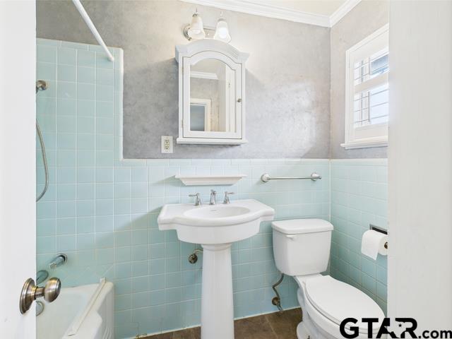 3323 S Keaton Ave, Tyler, TX 75701 - bathroom featuring crown molding, tub / shower combination, toilet, and tile walls