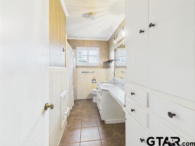 3323 S Keaton Ave, Tyler, TX 75701 - bathroom with tile patterned flooring, vanity, toilet, tile walls, and ornamental molding