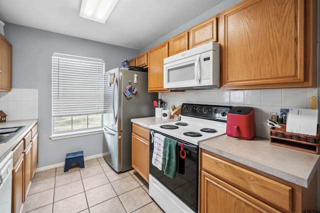 kitchen featuring white appliances, light tile patterned flooring, a sink, light countertops, and tasteful backsplash