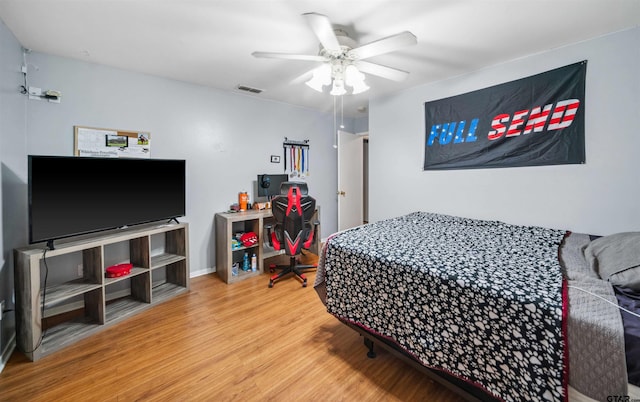 bedroom featuring visible vents, baseboards, ceiling fan, and wood finished floors