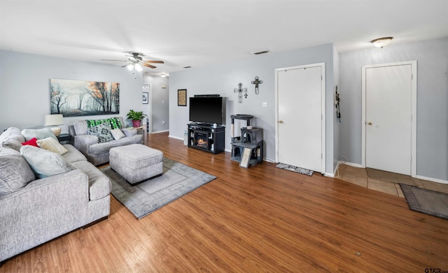 living area featuring visible vents, baseboards, a ceiling fan, and wood finished floors