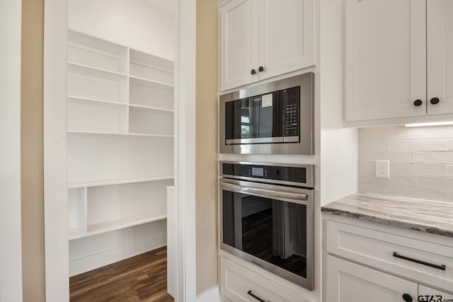 14524 Woodland Creek Dr, Tyler, TX 75706 - kitchen featuring stainless steel appliances, decorative backsplash, dark wood-type flooring, light stone counters, and white cabinetry