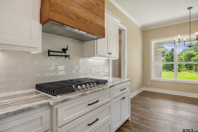 14524 Woodland Creek Dr, Tyler, TX 75706 - kitchen featuring stainless steel gas cooktop, a chandelier, crown molding, custom exhaust hood, and decorative backsplash