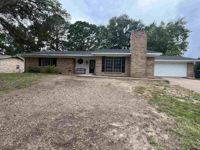 ranch-style house featuring brick siding, driveway, a chimney, and an attached garage