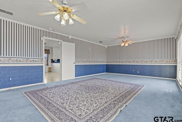 empty room with ceiling fan, ornamental molding, and carpet flooring