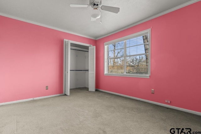 unfurnished bedroom with crown molding, light colored carpet, a closet, and ceiling fan