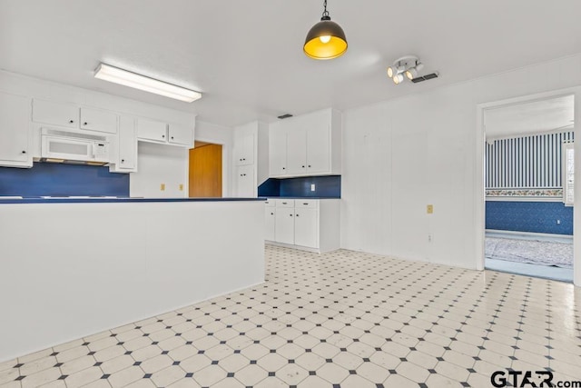 kitchen featuring decorative light fixtures and white cabinetry