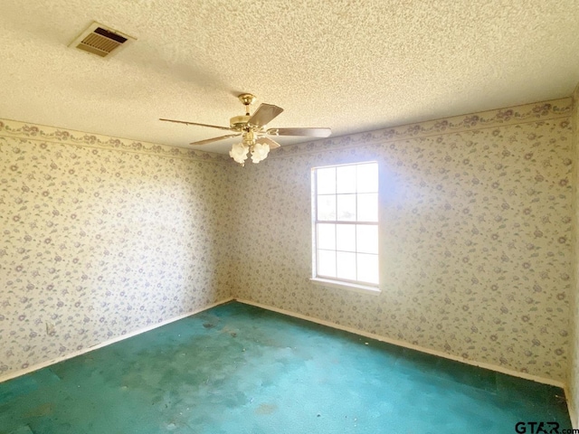 unfurnished room with a textured ceiling, visible vents, and wallpapered walls