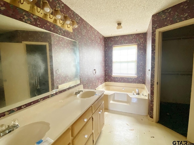 full bath featuring a garden tub, a sink, a textured ceiling, and wallpapered walls