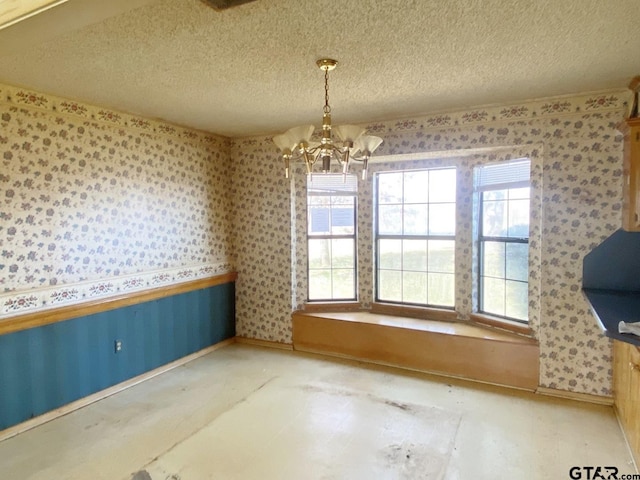 unfurnished dining area featuring a notable chandelier, a textured ceiling, and wallpapered walls