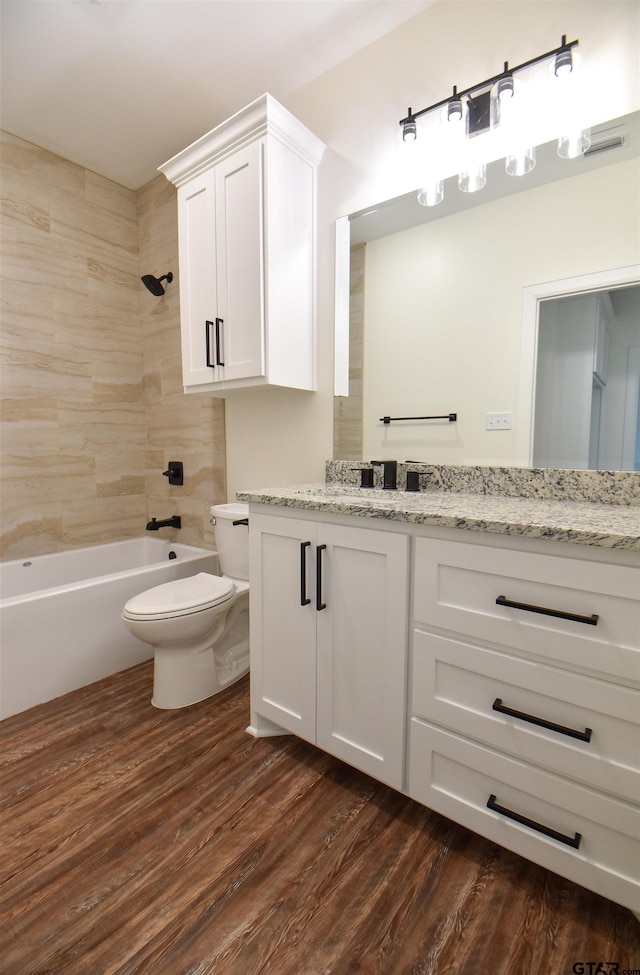 full bathroom with toilet, vanity, wood-type flooring, and tiled shower / bath