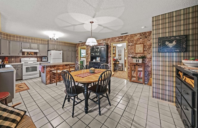 dining area with a textured ceiling, brick wall, and light tile patterned floors