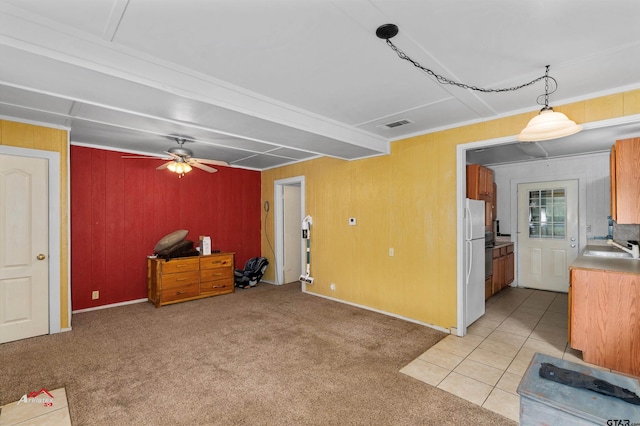 carpeted living room featuring wooden walls, sink, and ceiling fan