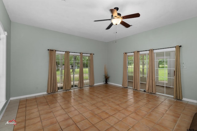 tiled empty room with a healthy amount of sunlight and ceiling fan