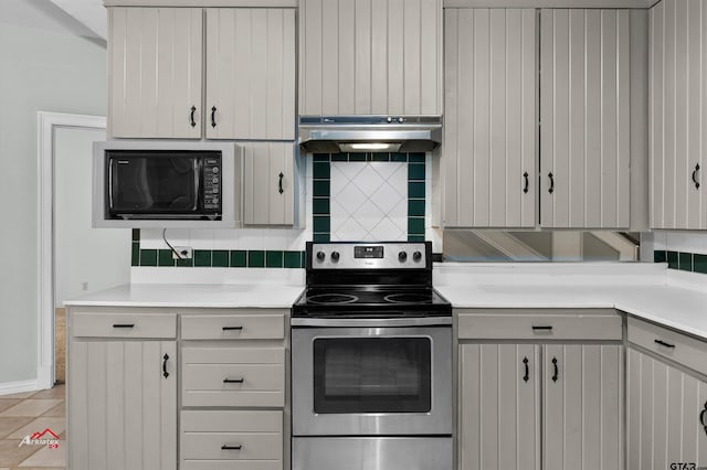 kitchen featuring white cabinets, decorative backsplash, black microwave, and stainless steel range with electric cooktop