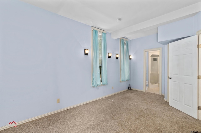 carpeted empty room featuring beamed ceiling