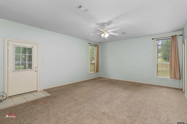 carpeted empty room with a wealth of natural light and ceiling fan