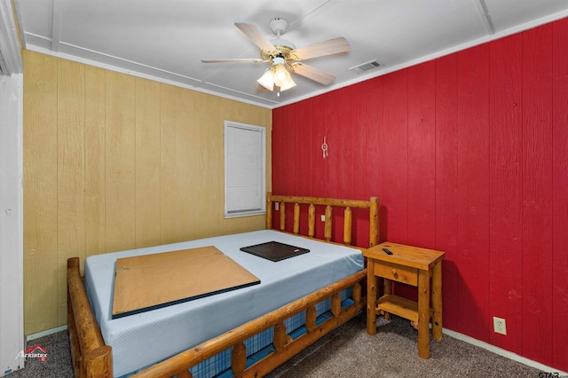 bedroom featuring wood walls, ceiling fan, and dark colored carpet