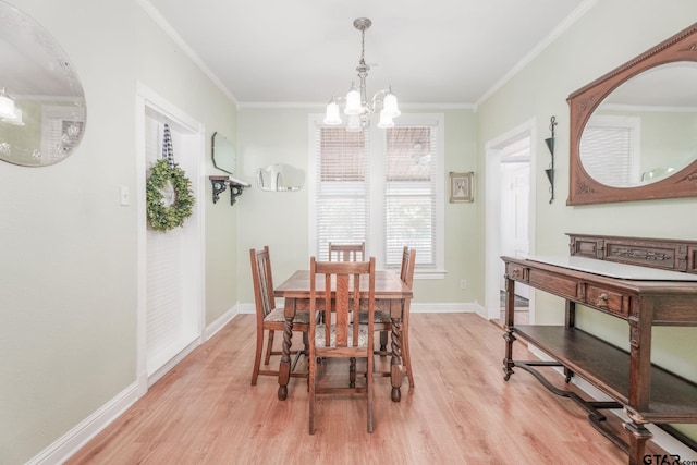 dining area with light wood-type flooring, ornamental molding, and a notable chandelier