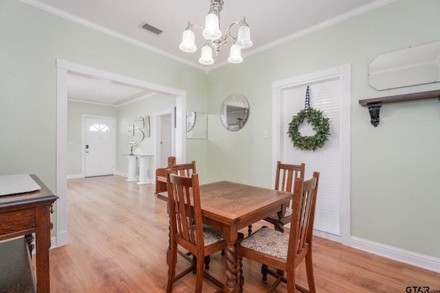 dining room featuring light hardwood / wood-style floors, ornamental molding, and a notable chandelier