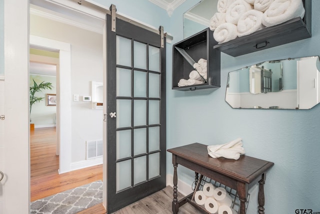 entryway featuring a barn door, crown molding, and hardwood / wood-style floors