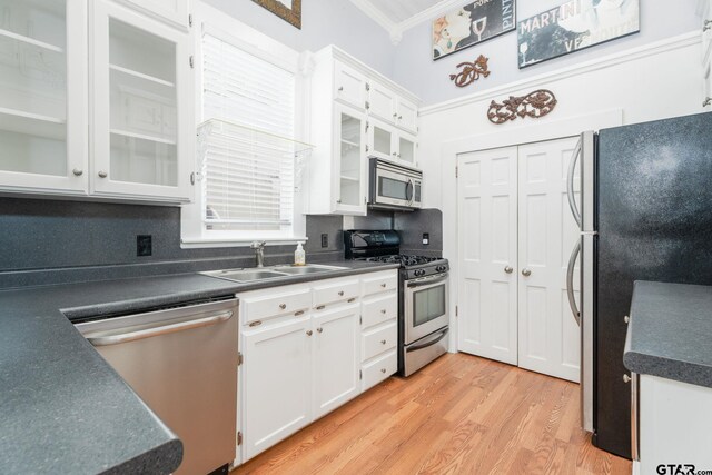 kitchen featuring white cabinetry, appliances with stainless steel finishes, decorative backsplash, light wood-type flooring, and sink