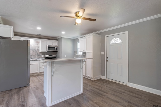 kitchen featuring a center island, backsplash, white cabinets, appliances with stainless steel finishes, and wood-type flooring