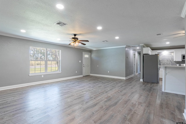 unfurnished living room with a textured ceiling, light hardwood / wood-style floors, and crown molding