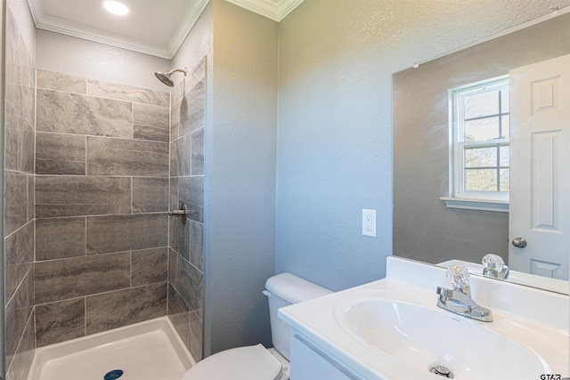 bathroom featuring tiled shower, crown molding, vanity, and toilet