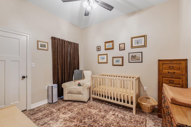 bedroom featuring a nursery area and ceiling fan