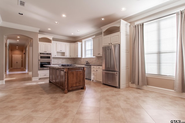 kitchen featuring ornamental molding, appliances with stainless steel finishes, a center island, and dark stone counters