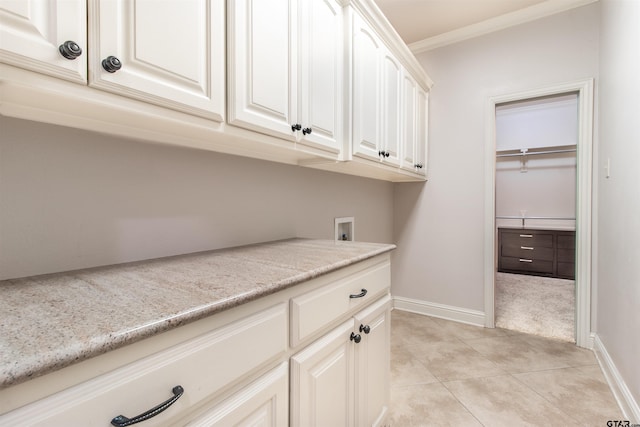 clothes washing area with light tile patterned flooring, cabinets, washer hookup, and crown molding