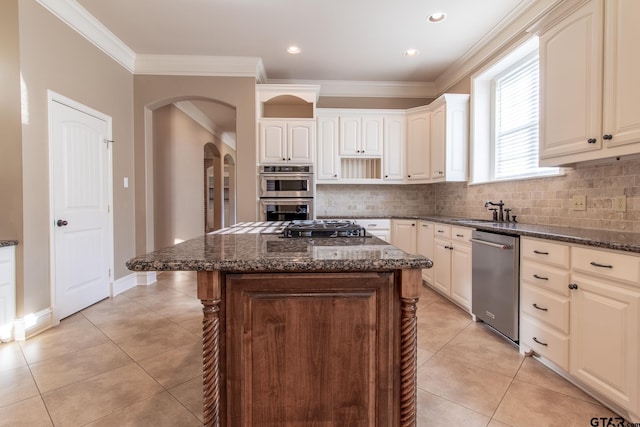 kitchen with dark stone countertops, a kitchen island, light tile patterned flooring, and appliances with stainless steel finishes