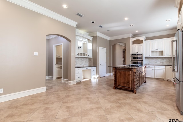 kitchen with a kitchen island, dark stone countertops, backsplash, light tile patterned floors, and stainless steel appliances